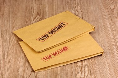 Envelopes with top secret stamp on wooden background clipart