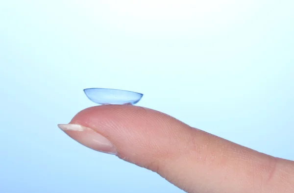 Kontakt lens mavi zemin üzerine parmak — Stok fotoğraf