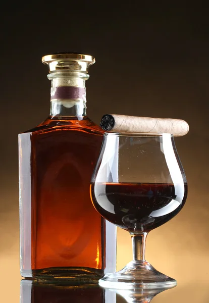 Bottle and glasss of brandy and cigar on brown background — Stock Photo, Image