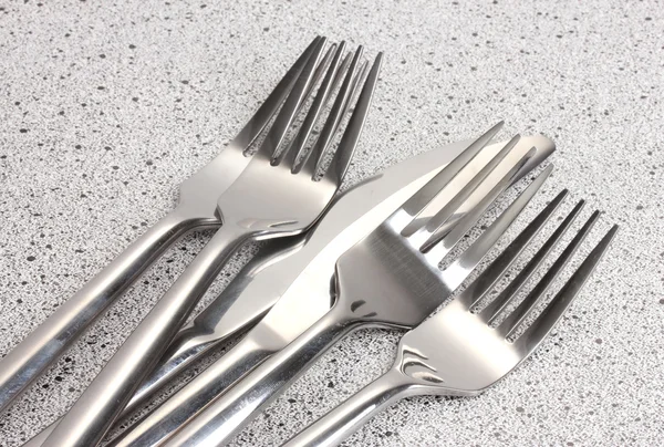 Forks and knives on marble table — Stock Photo, Image