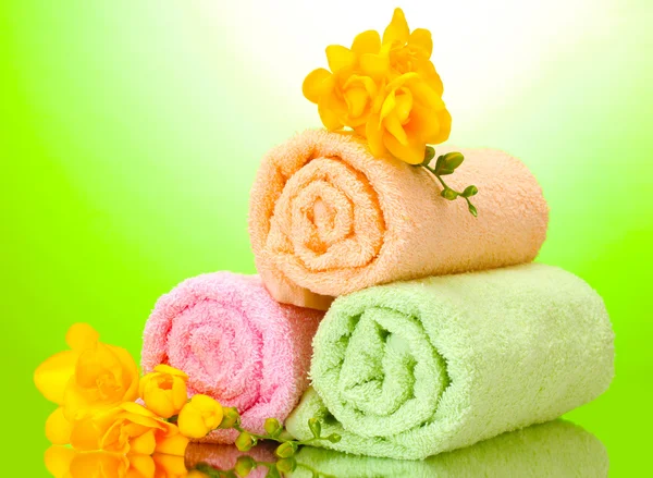 हिरव्या पिवळ्या पार्श्वभूमीवर रंगीत टॉवेल्स आणि फुले — स्टॉक फोटो, इमेज