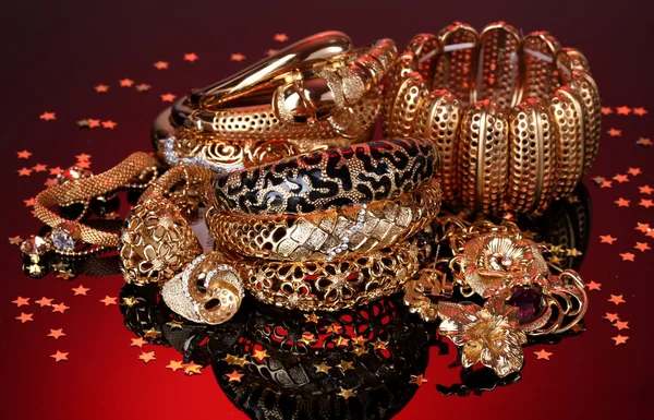 Belas jóias douradas no fundo vermelho — Fotografia de Stock