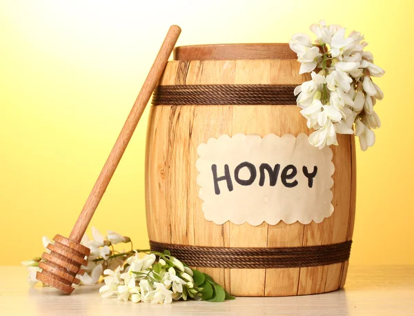 Sweet honey in barrel with acacia flowers on wooden table on yellow background — Stock Photo, Image