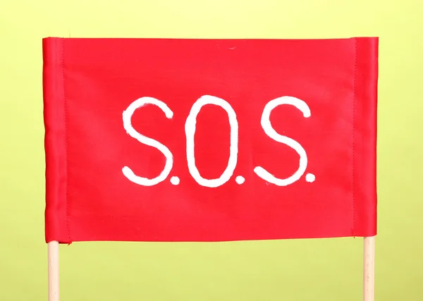 Sos 信号在绿色背景上的红布上写的 — 图库照片