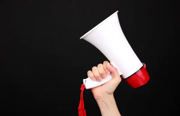 Red and white megaphone in hand isolated on black — Stock Photo, Image