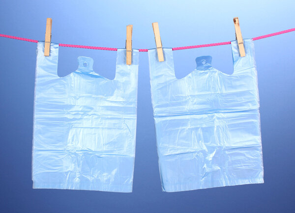 Целофановые мешки висят на веревке на синем фоне
