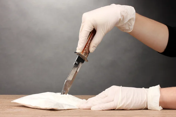 Pacotes de abertura de cocaína com uma faca na mesa de madeira em fundo cinza — Fotografia de Stock