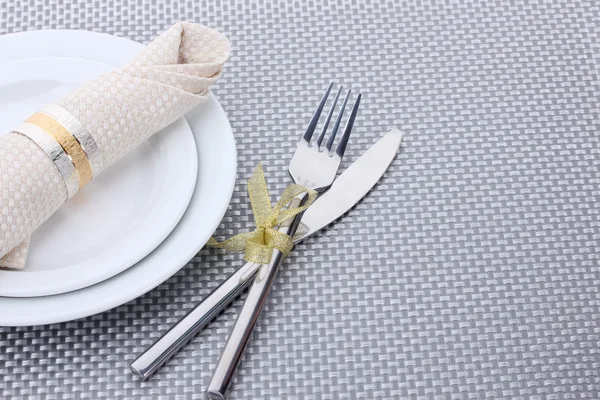 Vita tomma tallrikar med gaffel och kniv bundna med ett band på en grå duk — Stockfoto