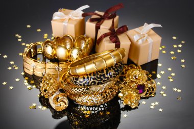 Beautiful golden jewelry and gifts on grey background clipart