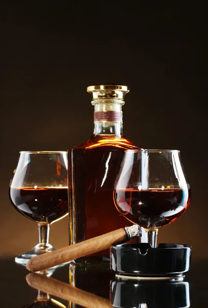 Botella y vasos de brandy y cigarro sobre fondo marrón — Foto de Stock
