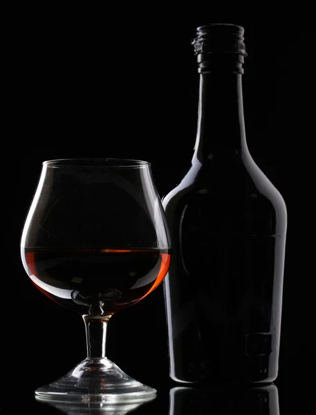 Vaso de brandy y botella sobre fondo negro —  Fotos de Stock