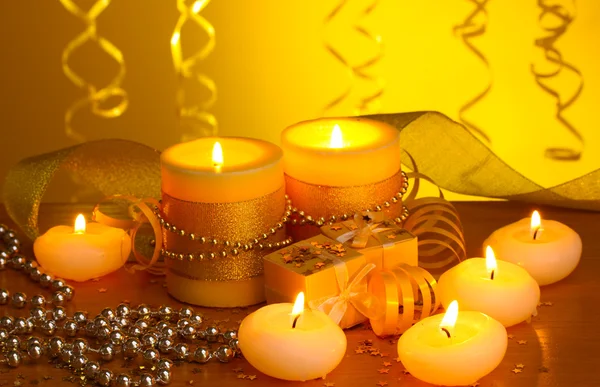 Όμορφα κεριά, δώρα και διακόσμηση σε ξύλινο τραπέζι σε κίτρινο φόντο — Φωτογραφία Αρχείου