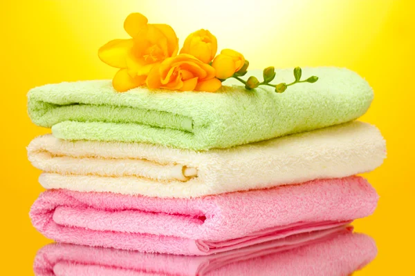 Colorful towels and flowers on yellow background — Stock Photo, Image