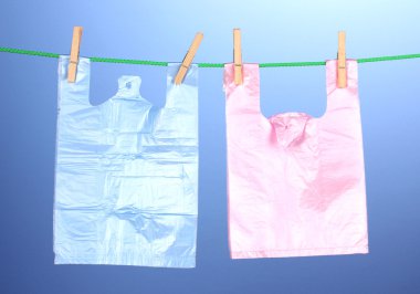 Cellophane bags hanging on rope on blue background clipart