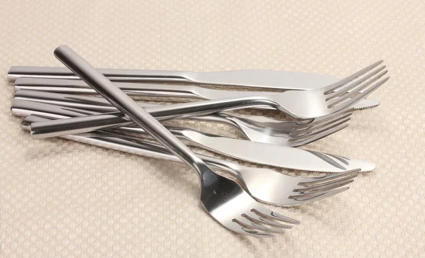 Gabeln und Messer auf einer beigen Tischdecke — Stockfoto