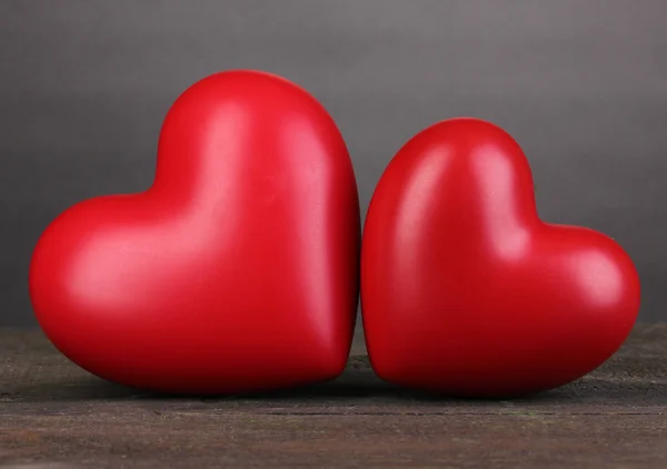 Two decorative red hearts on wooden table on grey background — Stock Photo, Image