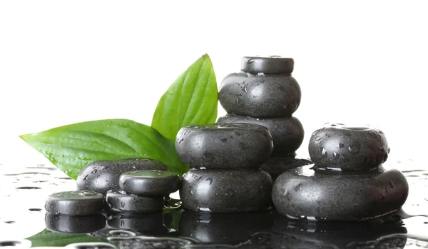 Spa stones with drops and green leaves on white background — Stock Photo, Image