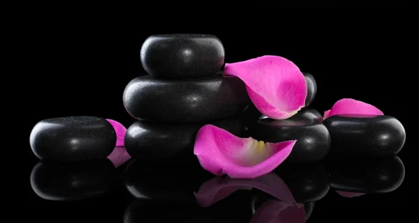 Spa stones and rose petals on black background — Stock Photo, Image