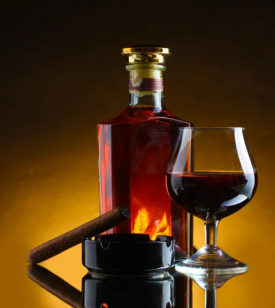 Botol dan gelas brendi dan cerutu di latar belakang coklat — Stok Foto