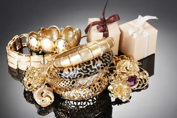 Güzel altın takı ve gri arka plan üzerinde hediyeler — Stok fotoğraf