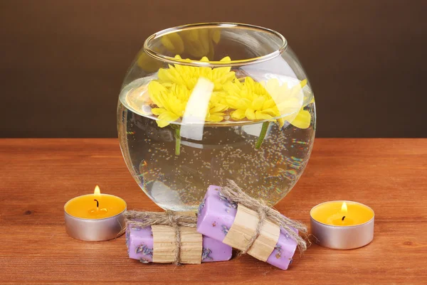 Spa kompozycja jasnych świece i kawałek mydła i żółte chryzantemy unoszące się na drewniane tła — Zdjęcie stockowe