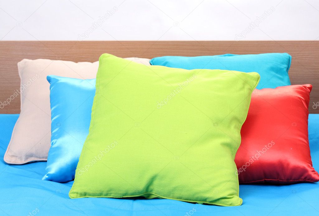 Bright pillows on bed on white background