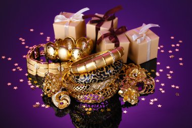 Beautiful golden jewelry and gifts on purple background clipart