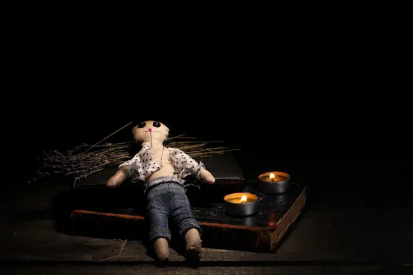 Chłopiec lalki Voodoo na drewnianym stole w blasku świec — Zdjęcie stockowe