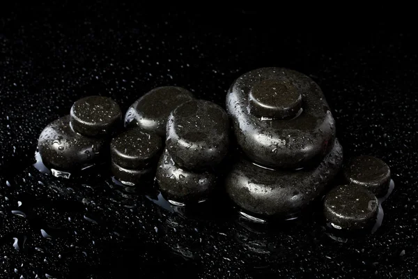 Pedras de spa com gotas no fundo preto — Fotografia de Stock