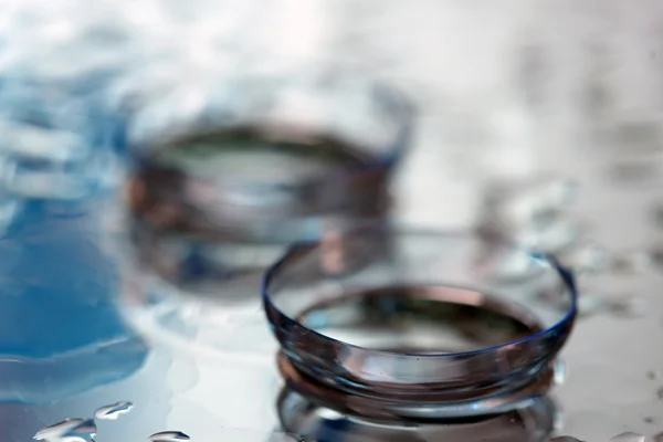 Lente de contacto con gotas sobre fondo azul — Foto de Stock