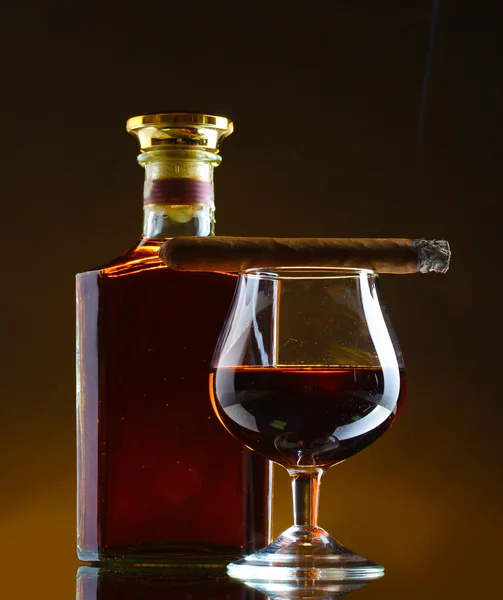 Bouteille et verre de brandy et cigare sur fond brun — Photo