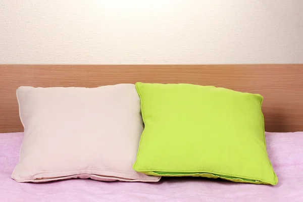 Ljusa kuddar på sängen på beige bakgrund — Stockfoto