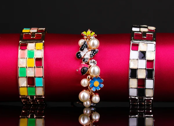 Tres pulseras de moda sobre tela rosa sobre fondo negro —  Fotos de Stock