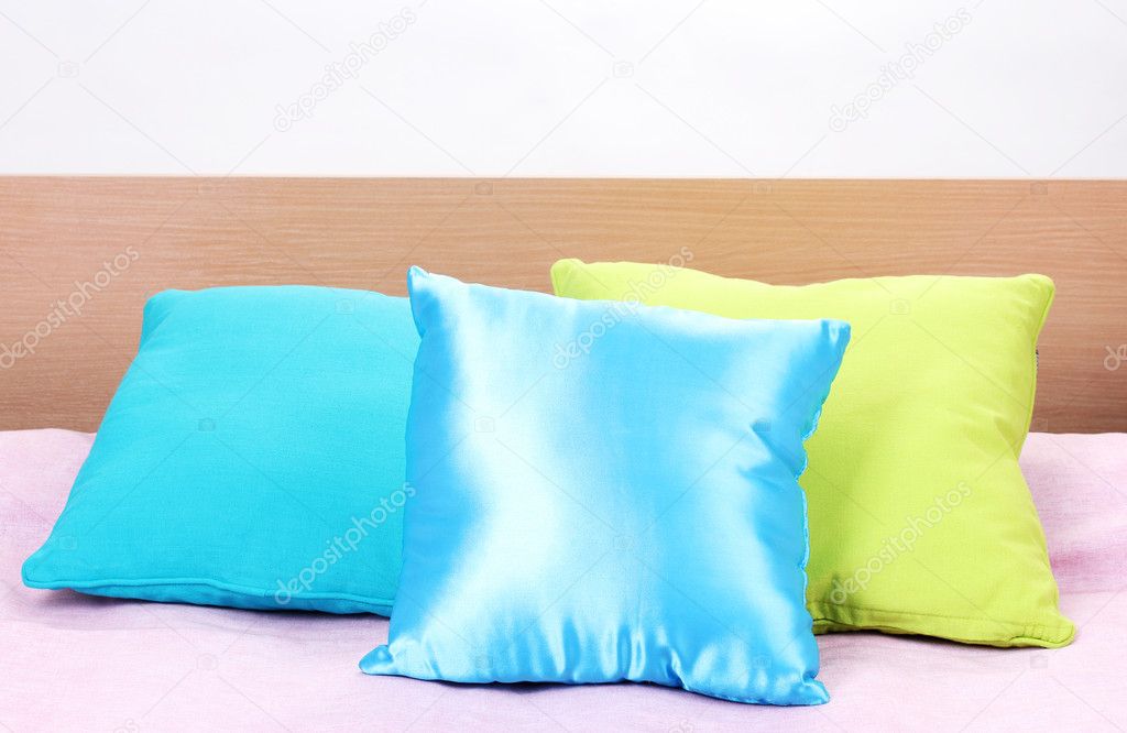 Bright pillows on bed on white background
