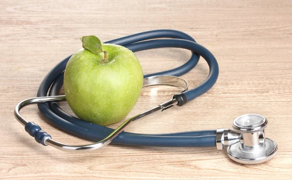 Sağlık stetoskop ve ahşap zemin üzerine yeşil elma — Stok fotoğraf