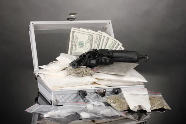可卡因和大麻在灰色的背景上的手提箱里的枪 — 图库照片