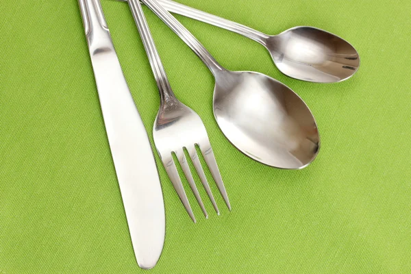 Fork, spoon and knife on a green tablecloth — Stock Photo, Image