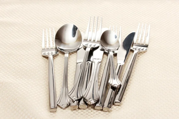 Forks, spoons and knives on a beige tablecloth — Stock Photo, Image