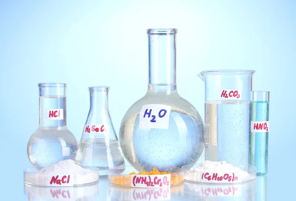 Reagenzgläser mit verschiedenen Säuren und Chemikalien auf blauem Hintergrund — Stockfoto
