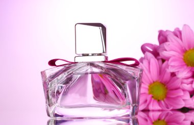 Women's perfume in beautiful bottle and flowers on pink background clipart