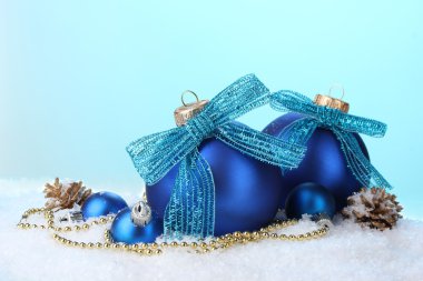 güzel mavi Noel topları ve konileri üzerinde kar mavi zemin üzerine