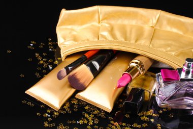 Beautiful golden makeup bag and cosmetics isolated on black clipart