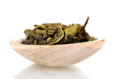 té verde seco en la cuchara de madera aislado en blanco