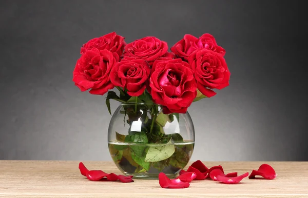 Vakre røde roser i vase på trebord på grå bakgrunn – stockfoto