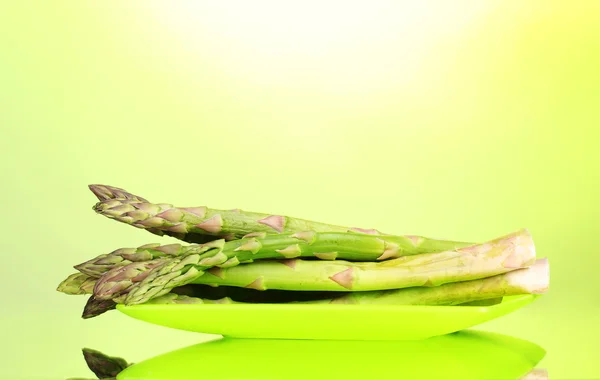Delicious asparagus on plate on green background — Stock Photo, Image