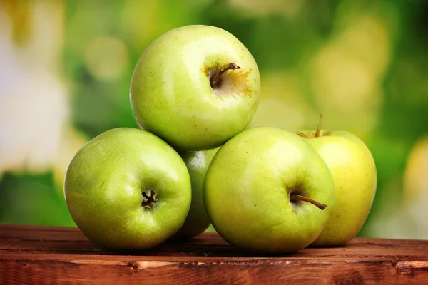 Ζουμερά πράσινα μήλα στο ξύλινο τραπέζι σε πράσινο φόντο — Φωτογραφία Αρχείου