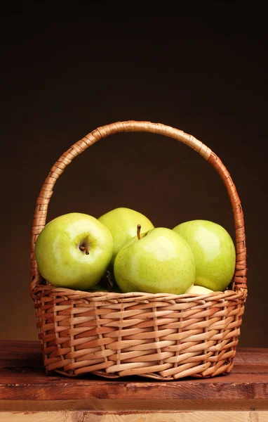 Pommes vertes juteuses dans le panier sur une table en bois sur fond brun — Photo