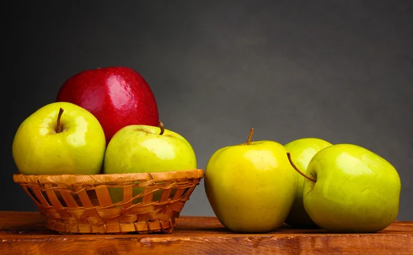 Ζουμερά γλυκά μήλα στο καλάθι στο ξύλινο τραπέζι σε γκρι φόντο — Φωτογραφία Αρχείου