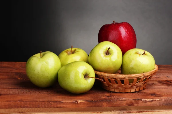 在灰色的背景上的木桌上的篮子里多汁甜苹果 — 图库照片