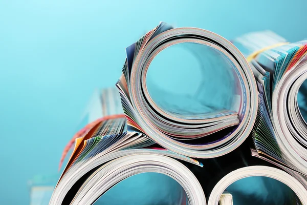 นิตยสารม้วนขึ้นบนพื้นหลังสีฟ้า — ภาพถ่ายสต็อก